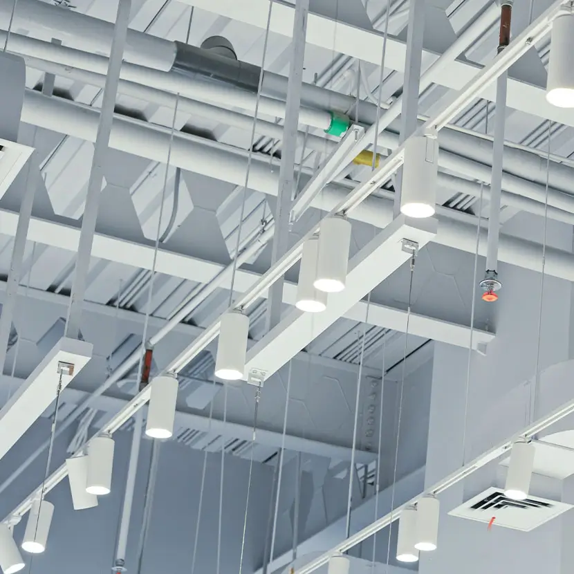 Building ceiling with exposed structural beams, HVAC ducts, and electrical conduits for real-time monitoring